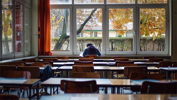 دانش آموزی تنها در کلاس در حال درس خواندن است