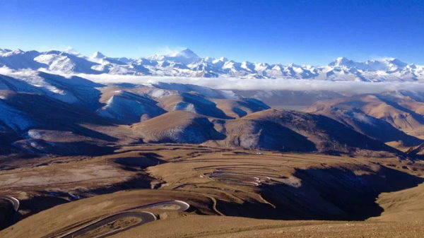 تبت با نمایی از کوهستان های پوشیده از برف در فاصله دور و تپه های خشک در نزدیکی