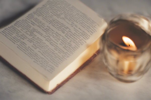 تصویر شمعی که کنار کتابی قرار دارد