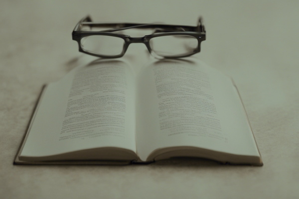 تصویر عینکی که نزدیک کتابی قرار دارد