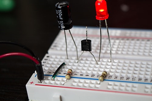 چند قطعه الکترونیکی شامل LED، مقاومت و خازن روی یک برد - ساخت مدار چشمک زن