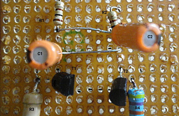 اتصال دو خازن و دو ترانزیستور به چهار مقاومت روی بورد با سیم‌های لحیم