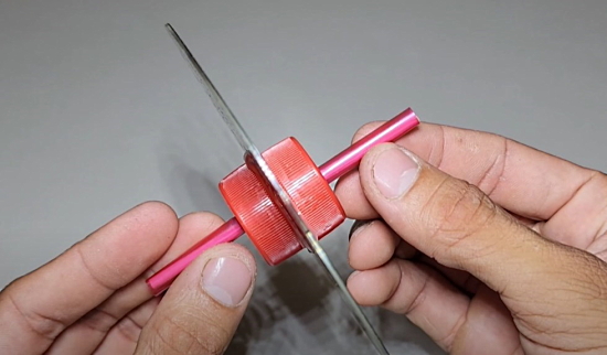 دو طرف یک دی وی دی دو در بطری آب معدنی قرمز و نی پلاستیکی چسب زده شده‌اند.