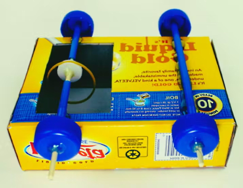 یک جعبه زرد کاغذی در تصویر به همراه چهار چرخ آبی